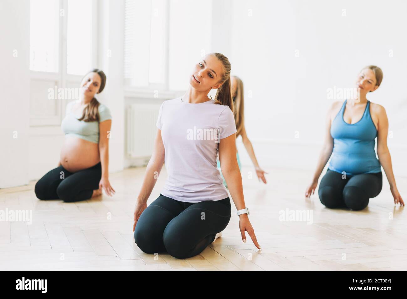 Group of pregnant women in sports uniforms with coach doing gymnastic