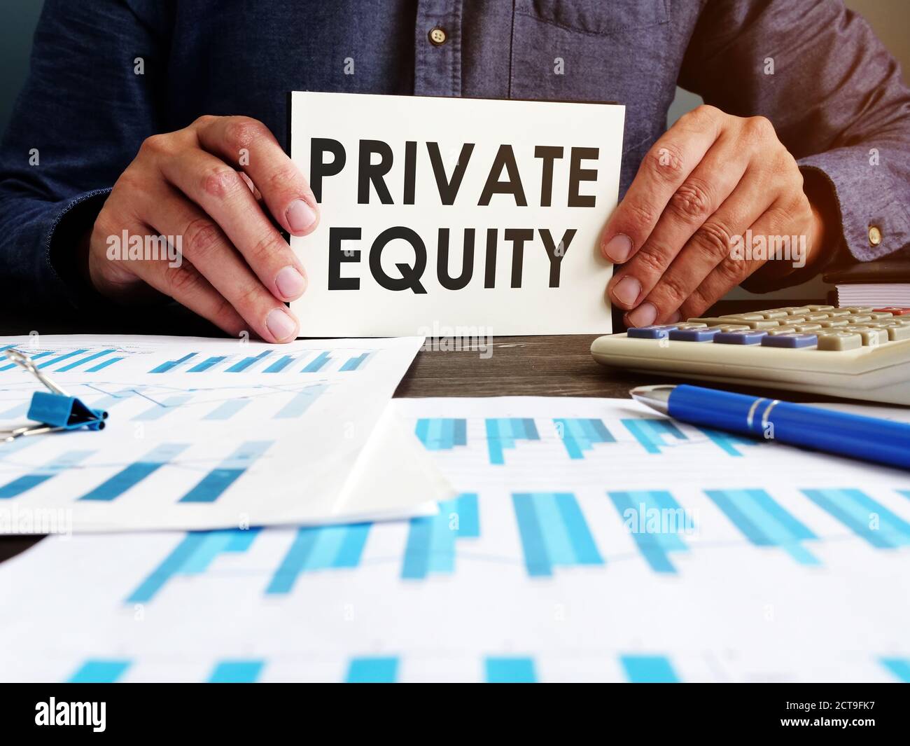 Private equity concept. Manager sitting at the table holds an inscription. Stock Photo