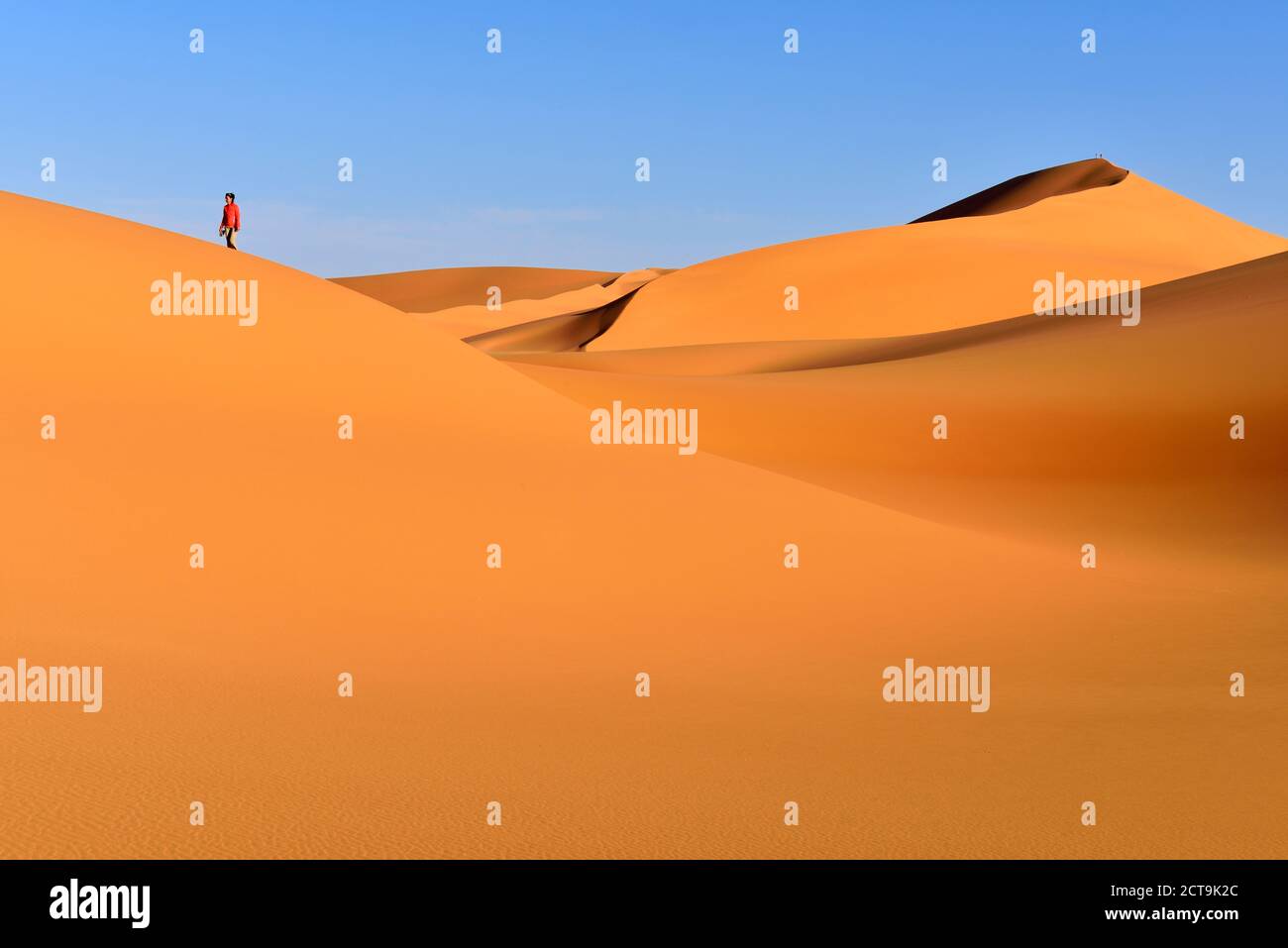 Algeria, Sahara, Tassili N'Ajjer National Park, Tadrart, woman walking in the dunes of Tehak Stock Photo