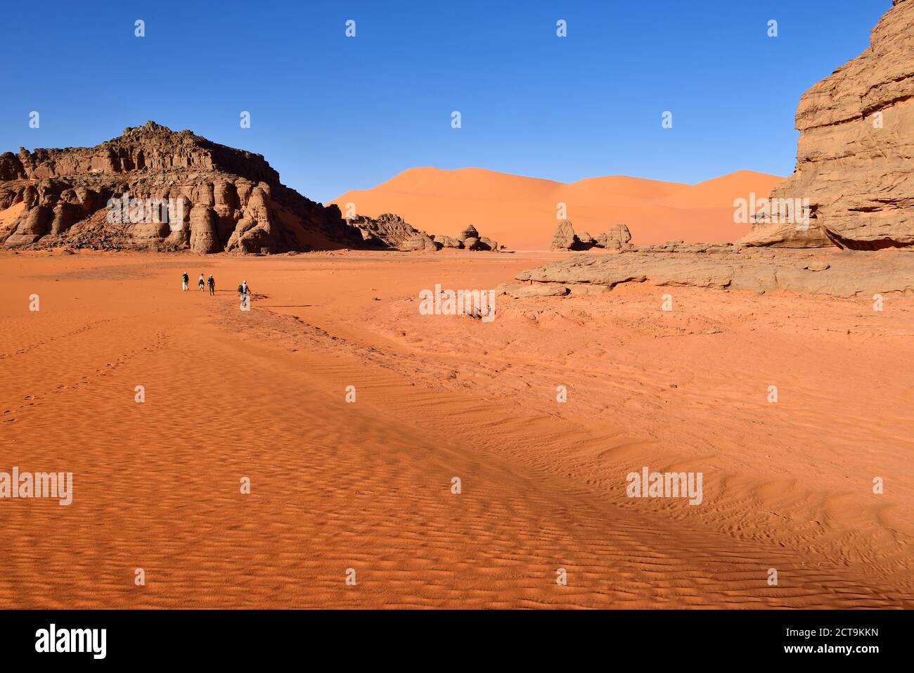 Algeria, Sahara, Tassili N'Ajjer National Park, People hiking between rocks and dunes of Tin Merzouga Stock Photo