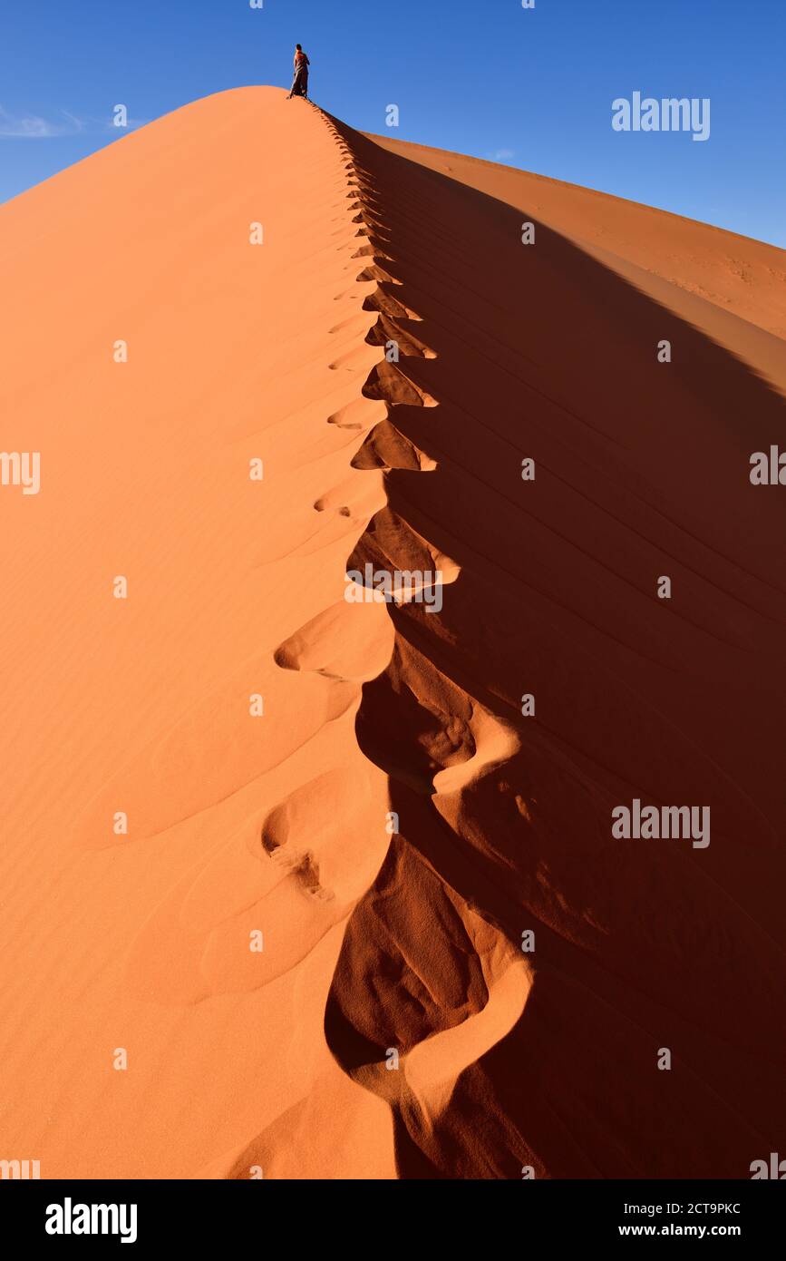 Algeria, Sahara, Tassili N'Ajjer National Park, Tadrart, woman hiking a dune of Tin Merzouga Stock Photo