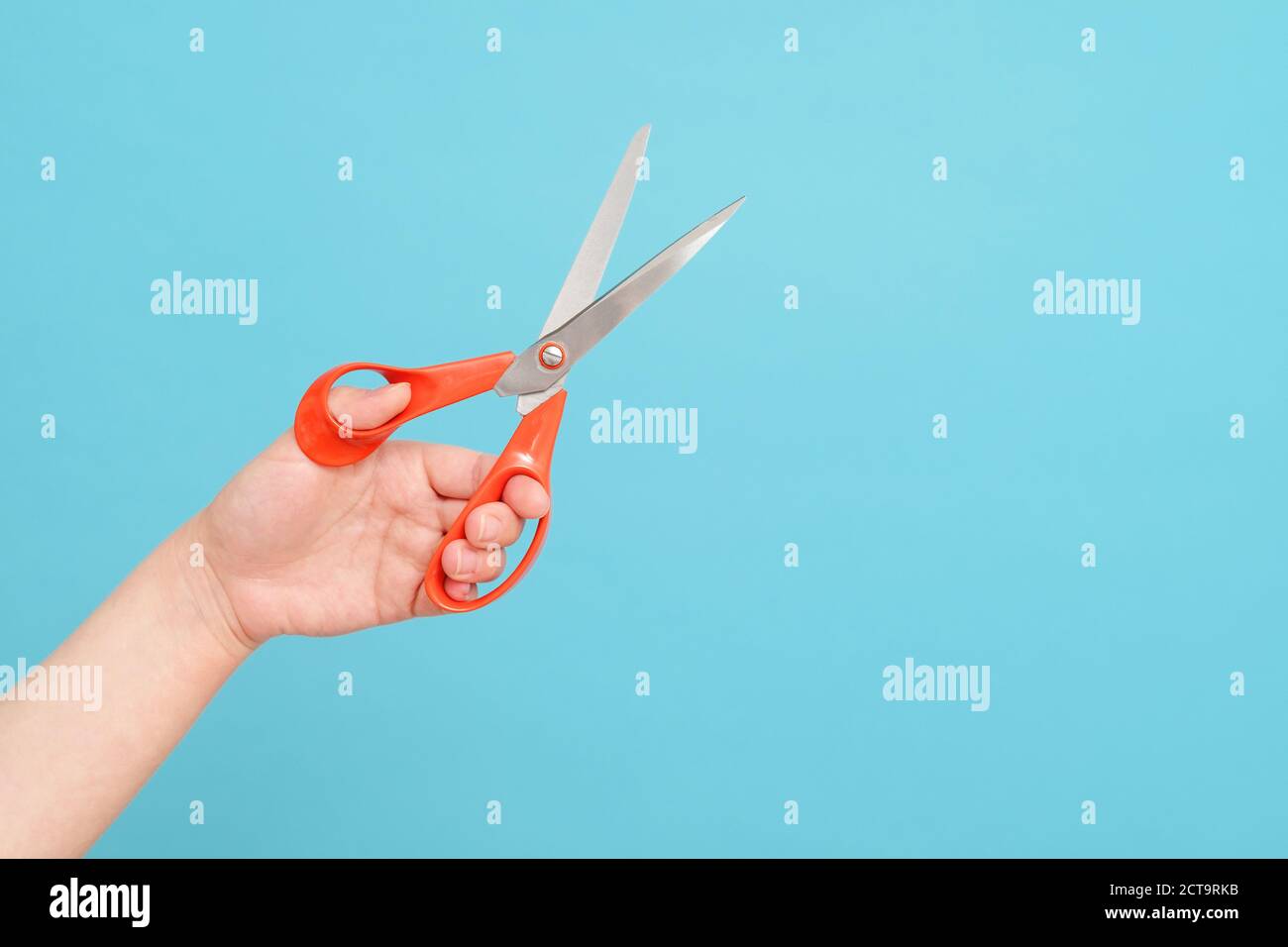 scissors in hands on blue background Stock Photo
