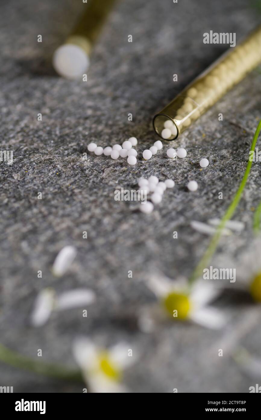 Bottle filled with pills fallen on table with chamomille flower Stock Photo