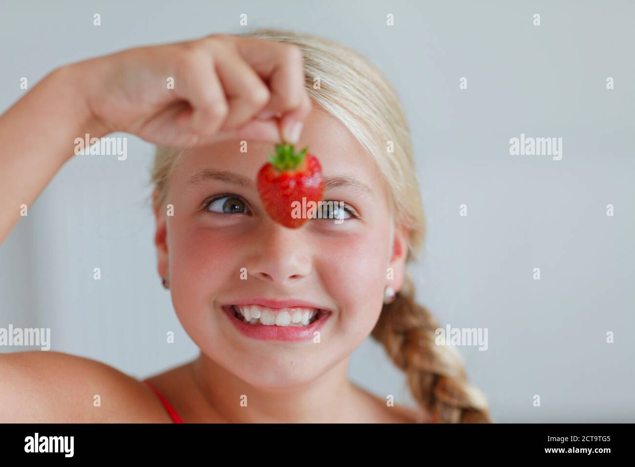 Smiling blond girl looking at strawberry Stock Photo