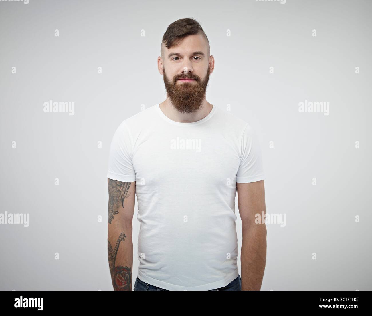 Portrait of smiling young man with shaved head, full beard and tattoo Stock Photo