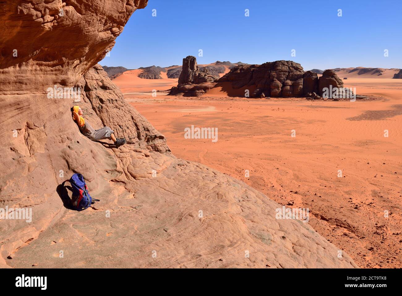 Algeria, Sahara, Tassili N'Ajjer National Park, Tadrart region, hiker leaning on rock face Stock Photo