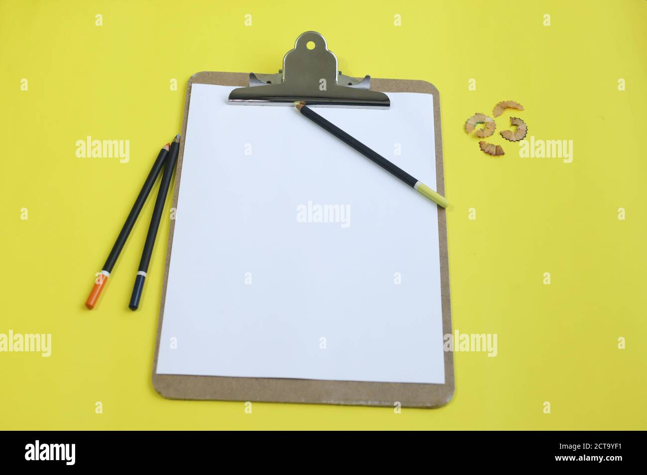 Shot of a drawing board with colorful  pencils on a yellow background Stock Photo