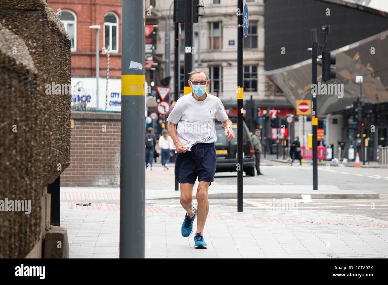 Picture taken on the day Coronavirus restrictions were implemented in Birmingham. Pictured a jogger wearing a face covering in Navigation Street, Birmingham. Stock Photo
