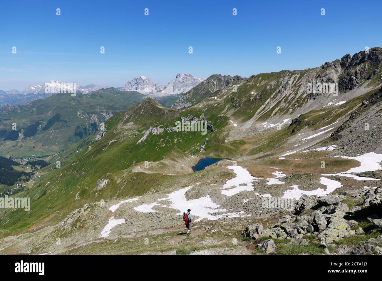 Switzerland, Grisons, Ratikon, Lake Grfiersee with Three towers and Sulzfluh mountains in background, person hiking at Austrian border Stock Photo