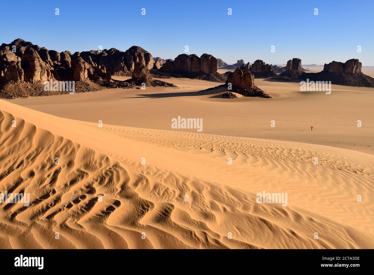Africa, Algeria, Sahara, Tassili N'Ajjer National Park, Sand dunes and rock formations at Tikobaouine, One woman standing in desert Stock Photo