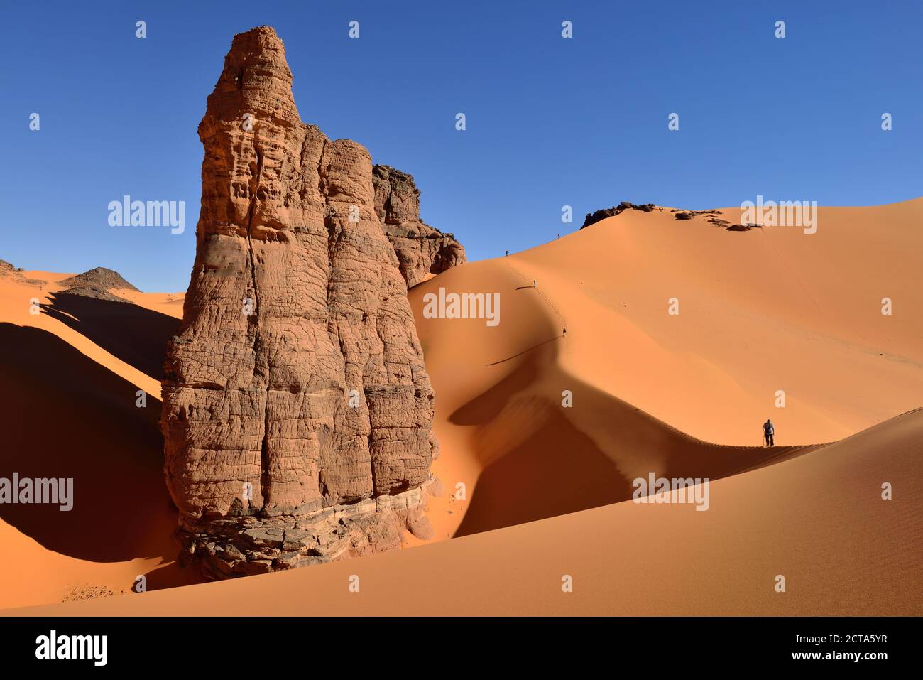 Algeria, Tassili n' Ajjer, Tadrart, Sahara, Tassili n' Ajjer National Park, view to sand dunes and rocks of Moul Nag with people at background Stock Photo