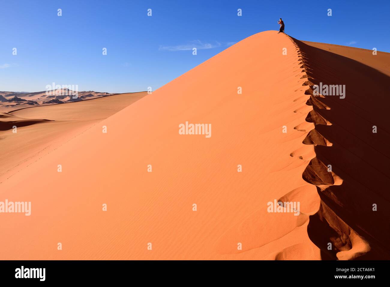 Algeria, Sahara, Tassili N'Ajjer National Park, Tadrart, woman hiking a dune of Tin Merzouga Stock Photo