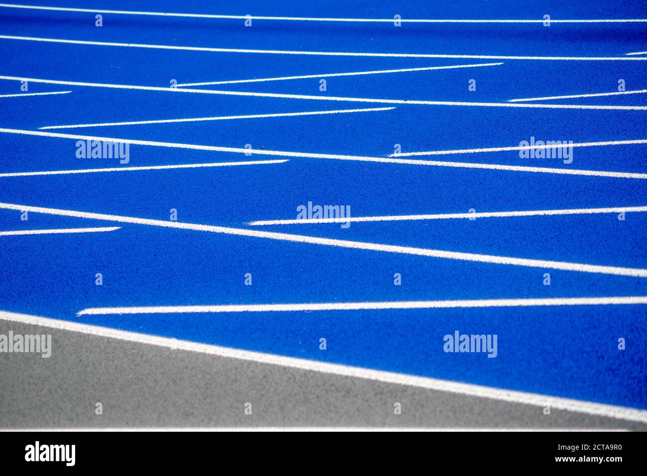 White lines on textured surface of blue running track. Stock Photo