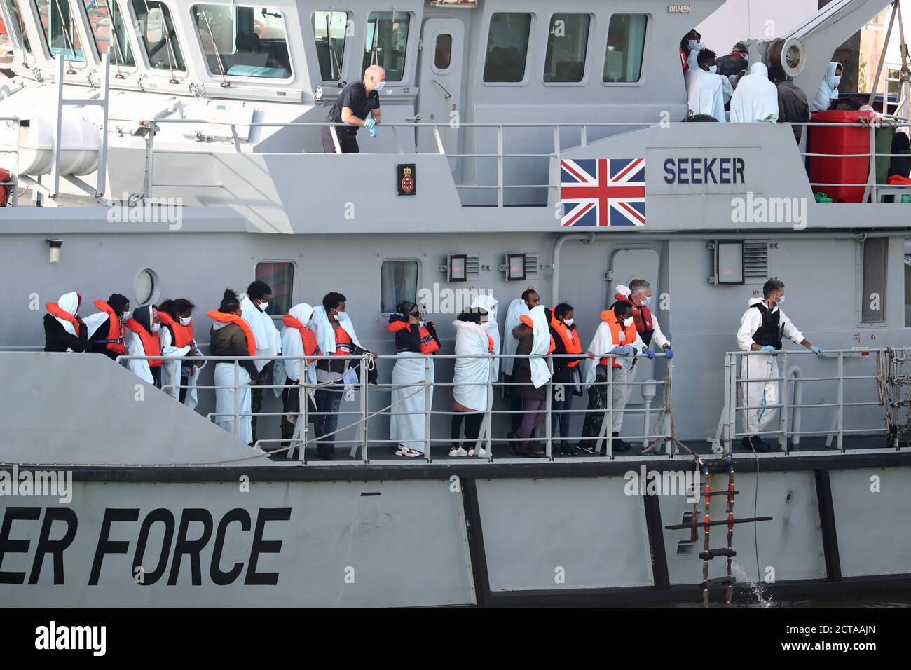 A group of people, thought to be migrants, on the deck of HMC Seeker, as they queue to disembark at Dover marina in Kent, after a small boat incident in the English Channel. Stock Photo