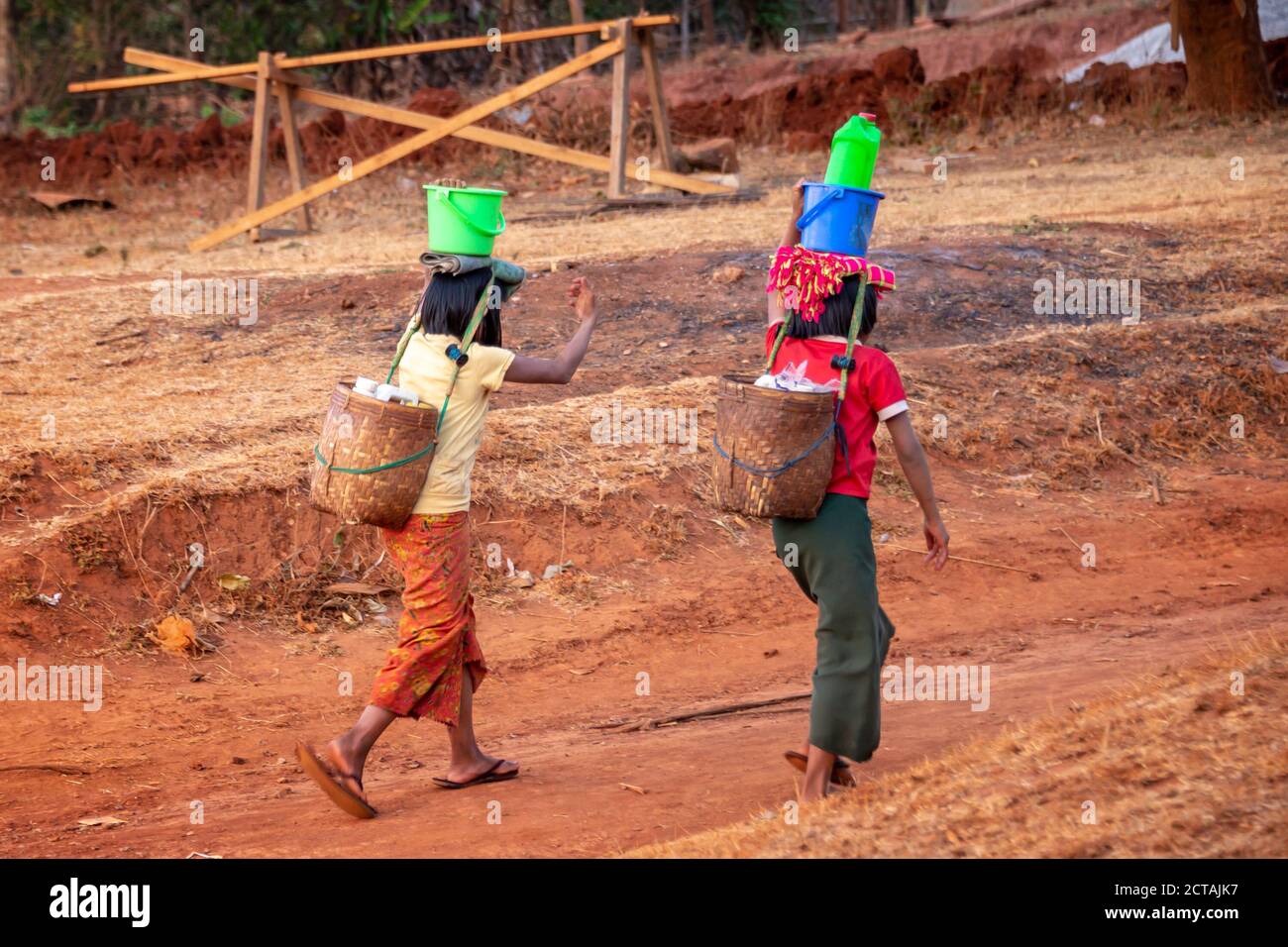 Two girls fetching water with plastic buckets and cans in Burma, Myanmar Stock Photo