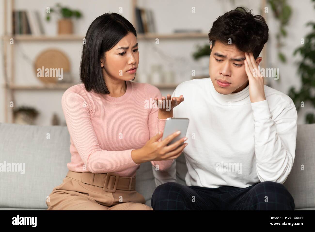 Asian Wife Showing Cheating Husband His Phone Suspecting Affair Indoors Stock Photo