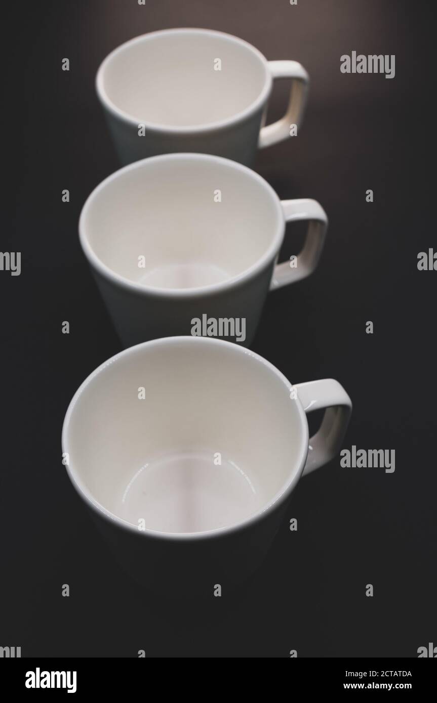 Vertical shot of three empty cups on a black surface Stock Photo