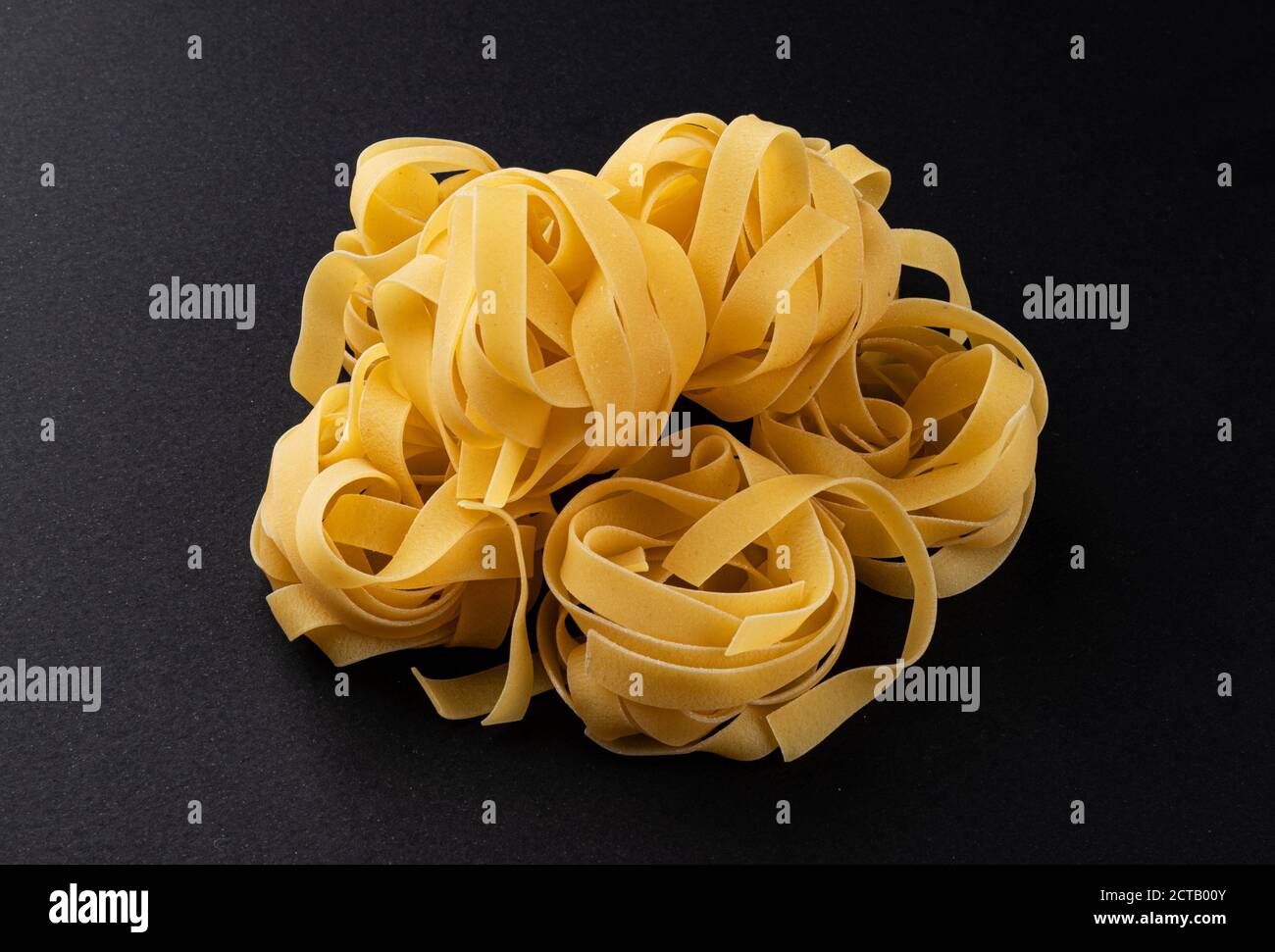 Raw fettuccine pasta isolated on black background Stock Photo Alamy