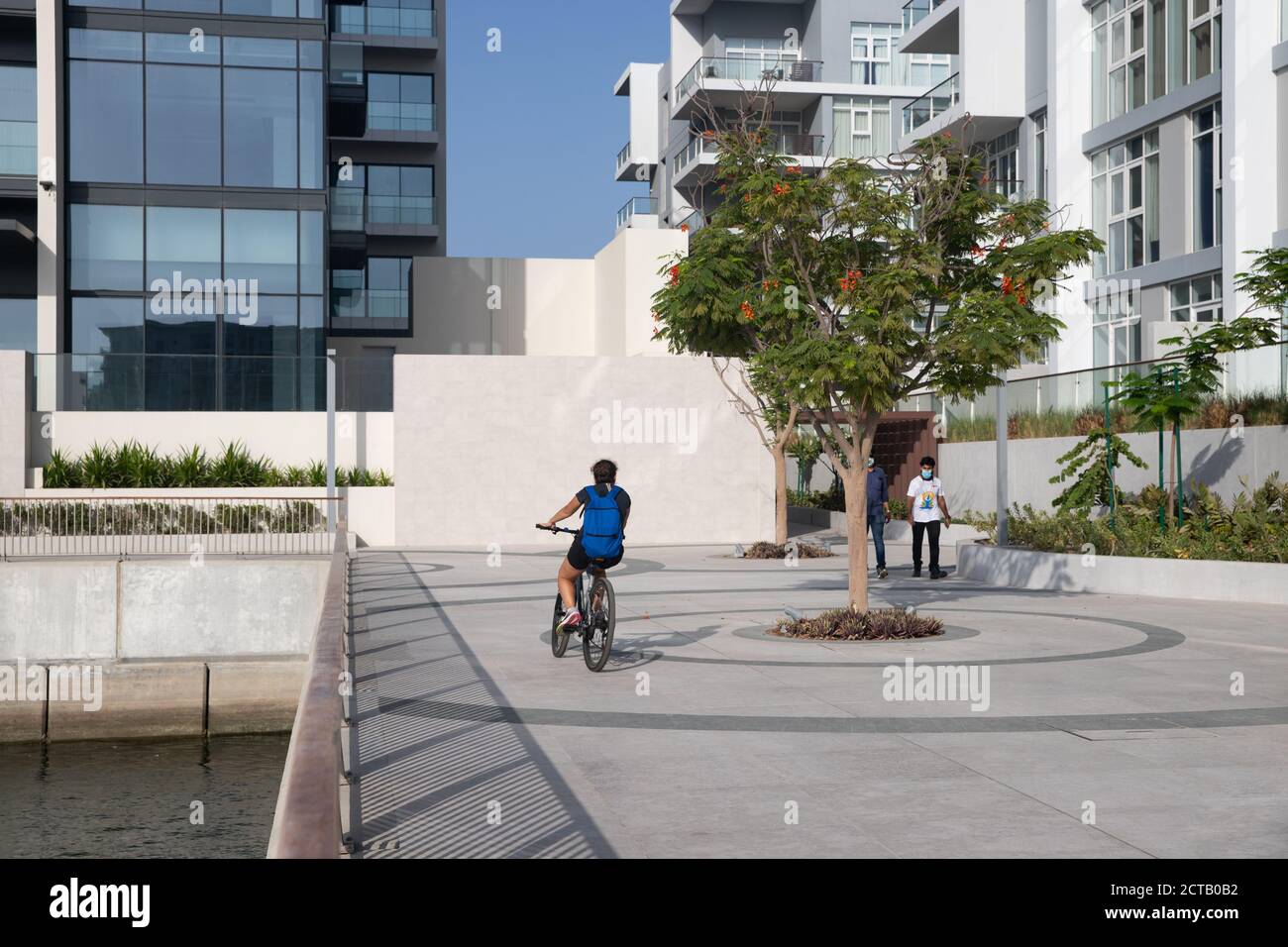 Man biking by the marina. Residential buildings. Apartments with balcony. Al Mouj, The Wave, Muscat, Sultanate of Oman. February 13, 2020 Stock Photo
