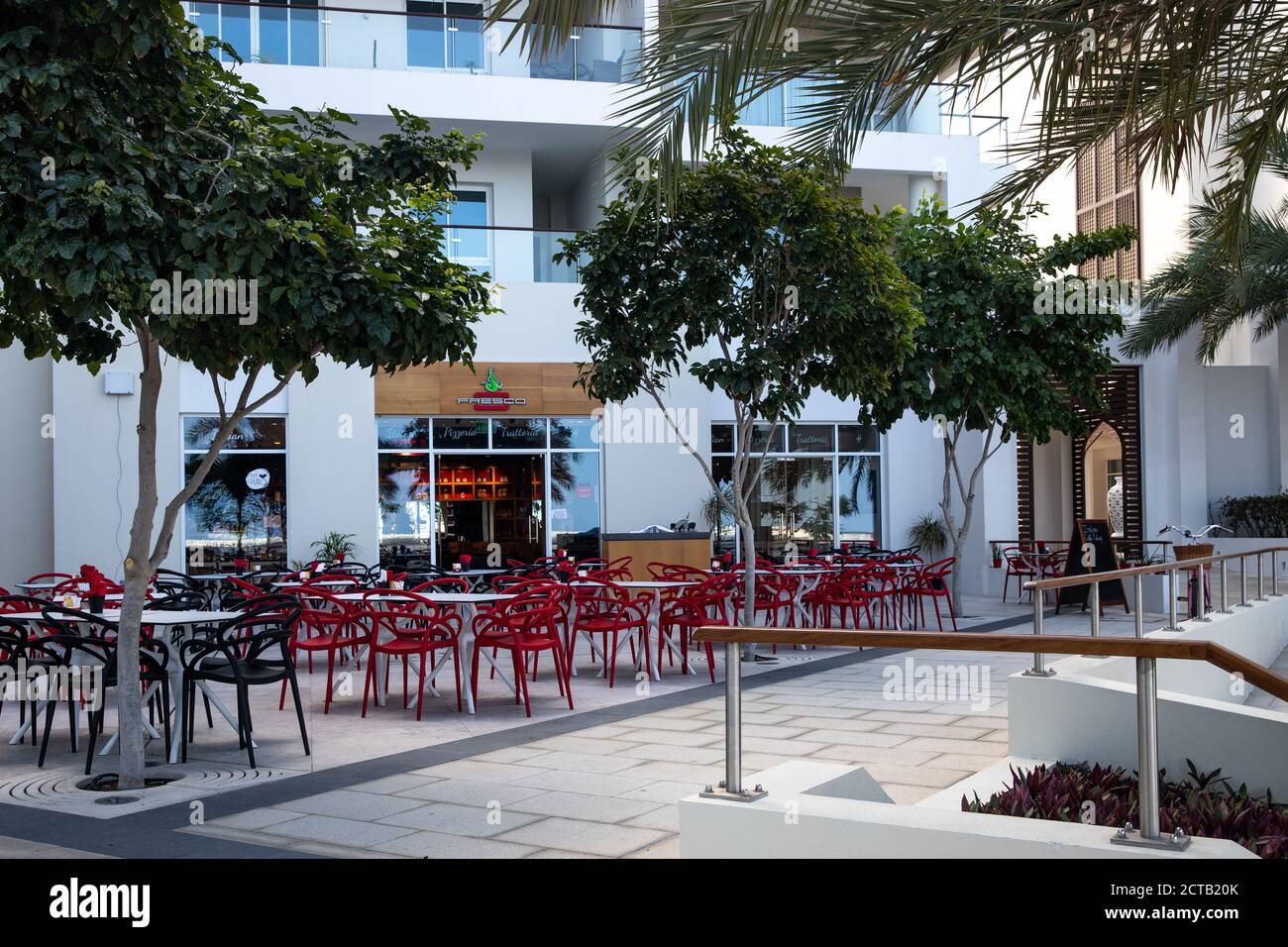 Seating area outside Fresco italian restaurant, close to the marina and residential buildings. Al Mouj, The Wave, Muscat, Sultanate of Oman. Stock Photo