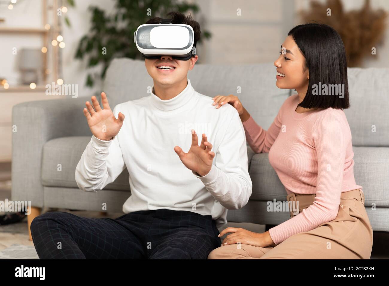 Asian Couple Using Virtual Reality Headset Having Fun At Home Stock Photo