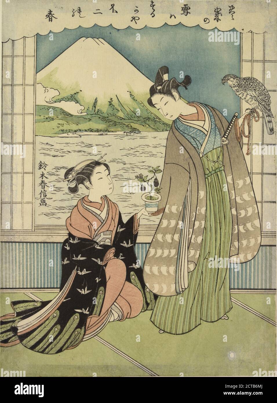 A young woman kneeling upon the floor of a room, handing a pot with an egg-plant growing in it to a young man with a falcon upon his wrist about to set forth on a hawking expedition.  Through an open window Fuji san is seen across an arm of the sea, still image, Prints, 1891 Stock Photo
