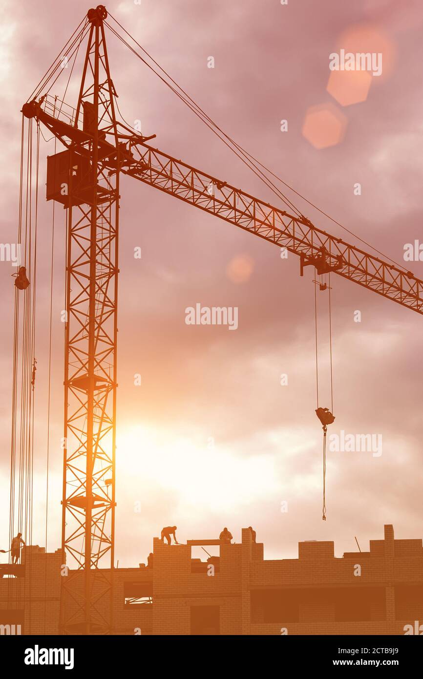 Silhouette of a team of construction workers in and a crane ...