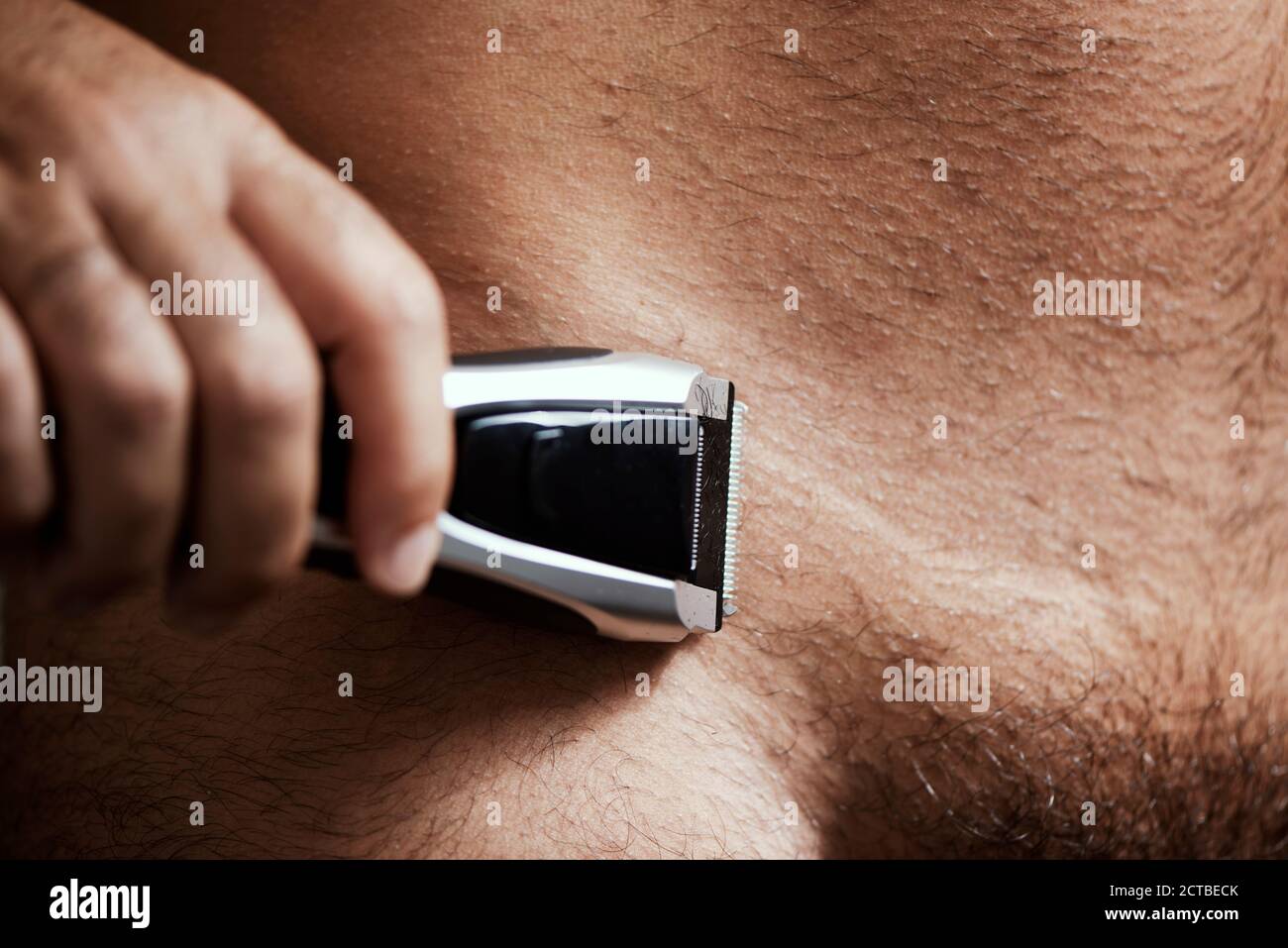 closeup of a young caucasian man in the bathroom trimming the hair of his pubes with an electric trimmer Stock Photo