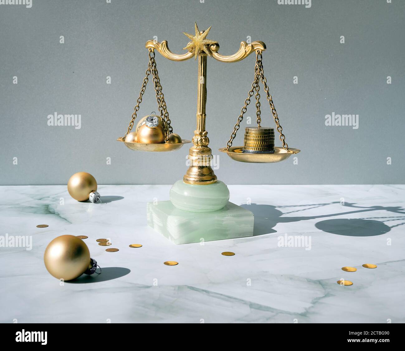 Cost of Christmas holidays concept. Weight scales, vintage balance with stack of coins and golden Xmas baubles. Stock Photo