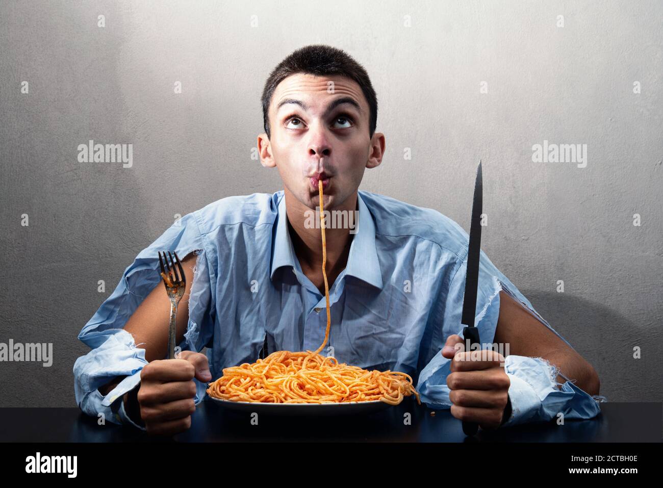Man eating spaghetti with tomato sauce hires stock photography and
