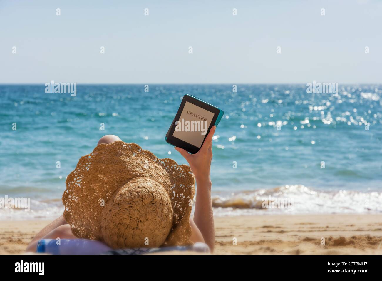 Woman relaxes while reading on the beach Stock Photo