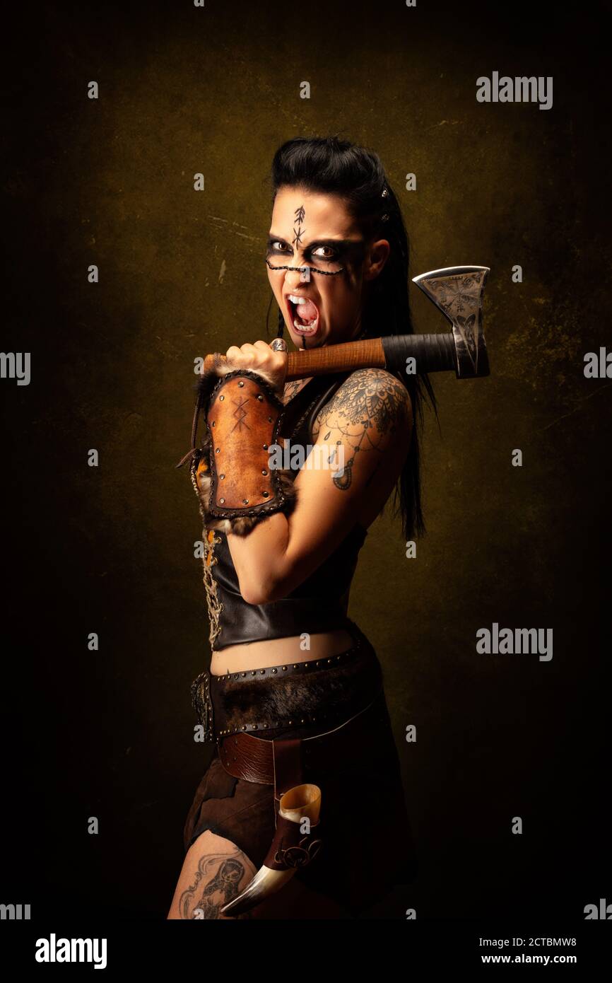 Portrait of a young tattooed Viking warrior, screaming, ax on shoulder Stock Photo