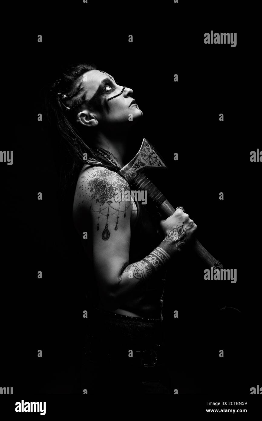 Portrait of a young tattooed Viking warrior with an ax on her shoulder Stock Photo