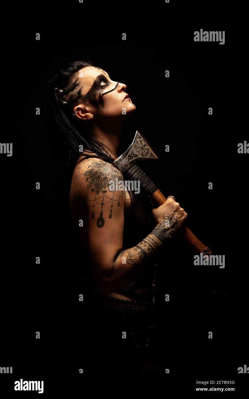 Portrait of a young tattooed Viking warrior with an ax on her shoulder Stock Photo