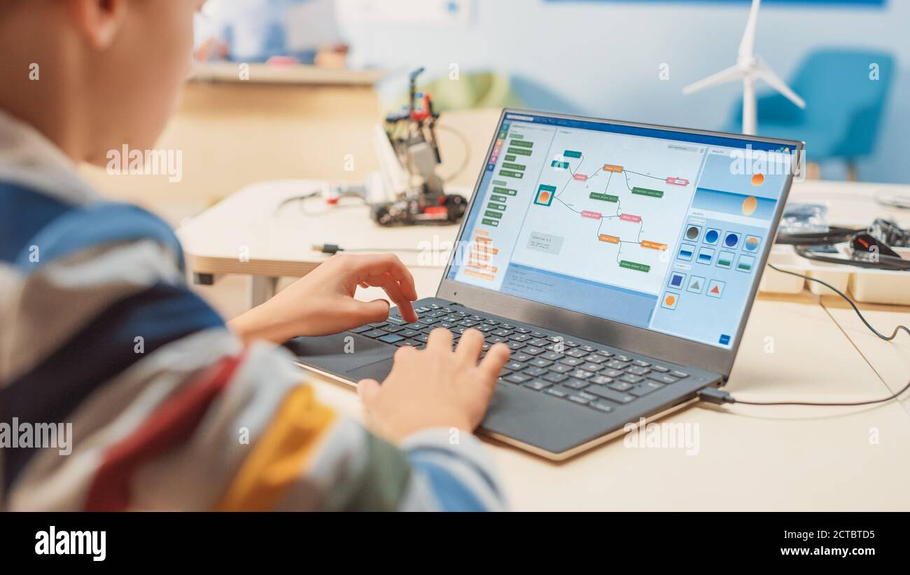 Smart Schoolboy Uses Laptop to Program Software for Robotics Engineering Class. Elementary School Science Classroom with Gifted Brilliant Children Stock Photo