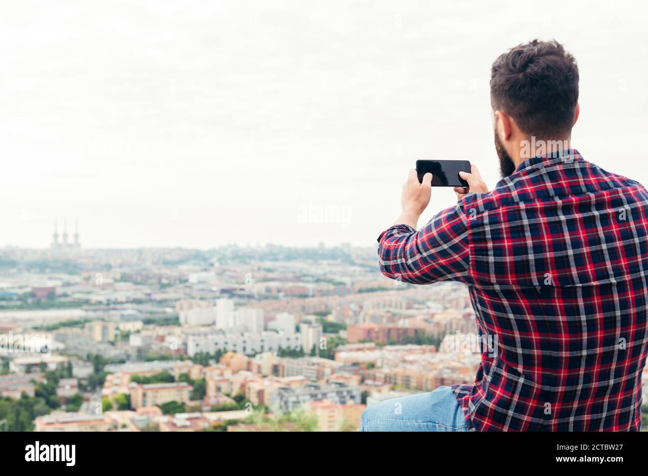 Man Using Mobile Back View back view of a man taking a photo with his mobile phone of the city ...
