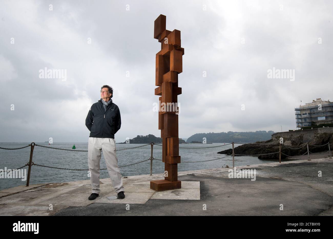 Sir Antony Gormley poses for a photograph next to his artwork 'Look II' on West Hoe Pier in Plymouth, which forms part of the 'Making It' exhibition, featuring new works by Antony Gormley, Kehinde Wiley and Lenore Antunes, at The Box museum in Plymouth, Devon. Stock Photo