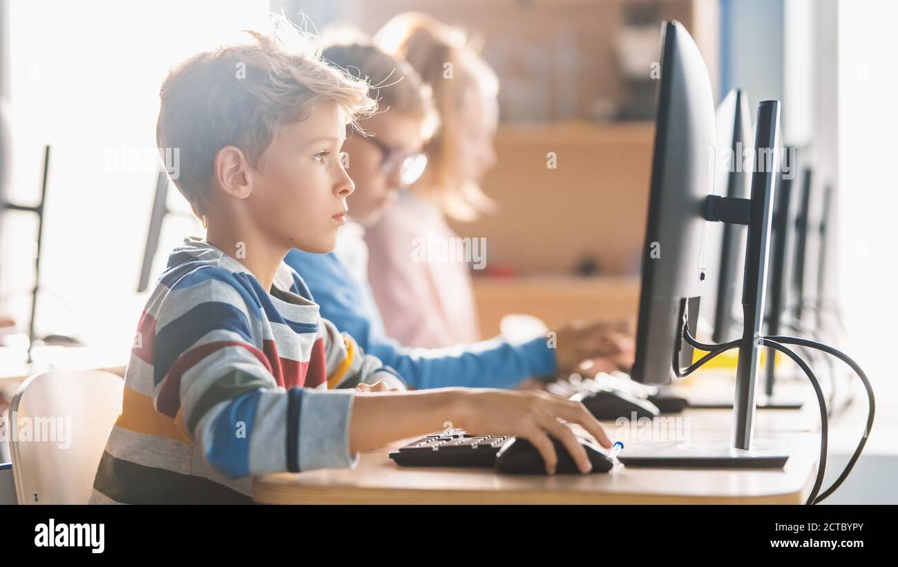 Elementary School Science Classroom: Smart Little Schoolchildren Sitting in Row and Work on Personal Computers, Learn Programming Language for Stock Photo