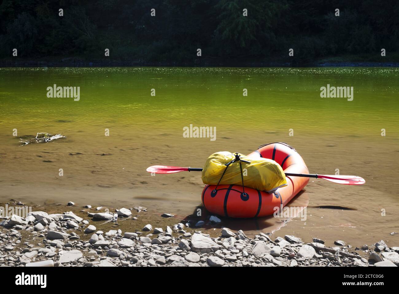 Orange packraft rubber boat with backpack on a river. Packrafting. Active lifestile concept Stock Photo
