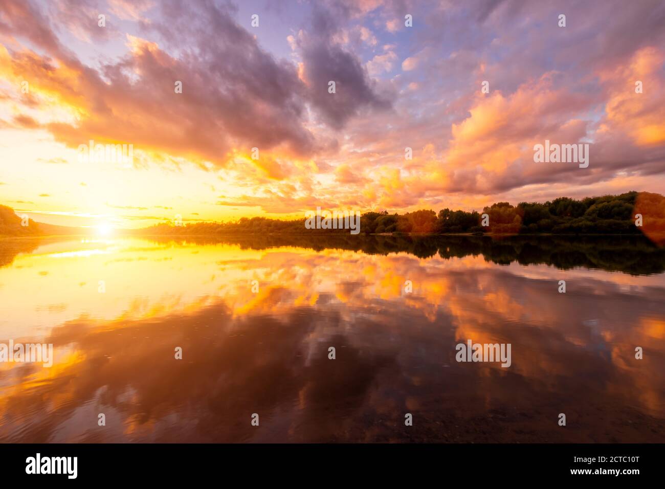 A sunset or sunrise scene over a lake or river with dramatic cloudy ...