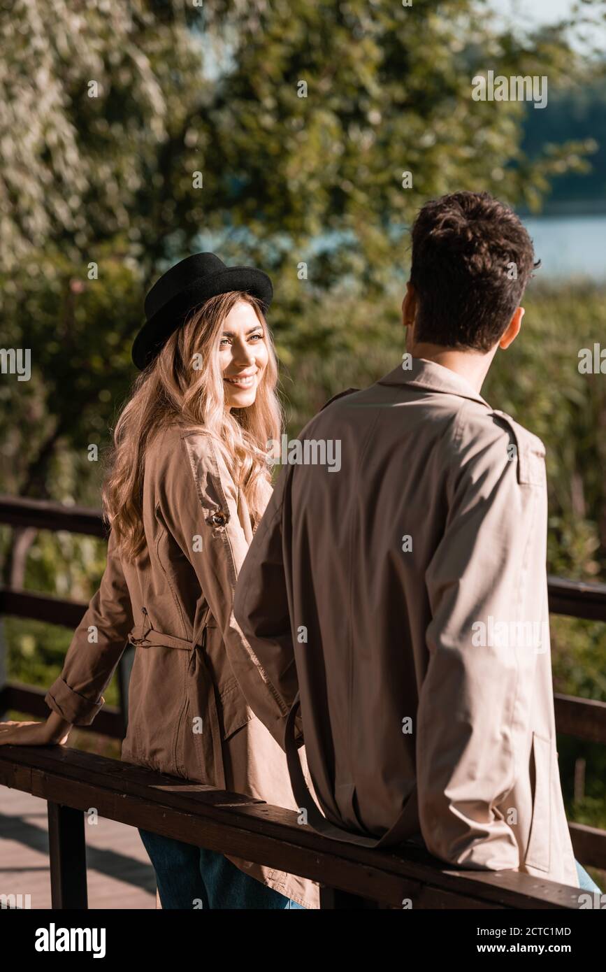 blonde woman in hat looking at boyfriend in trench coat Stock Photo - Alamy