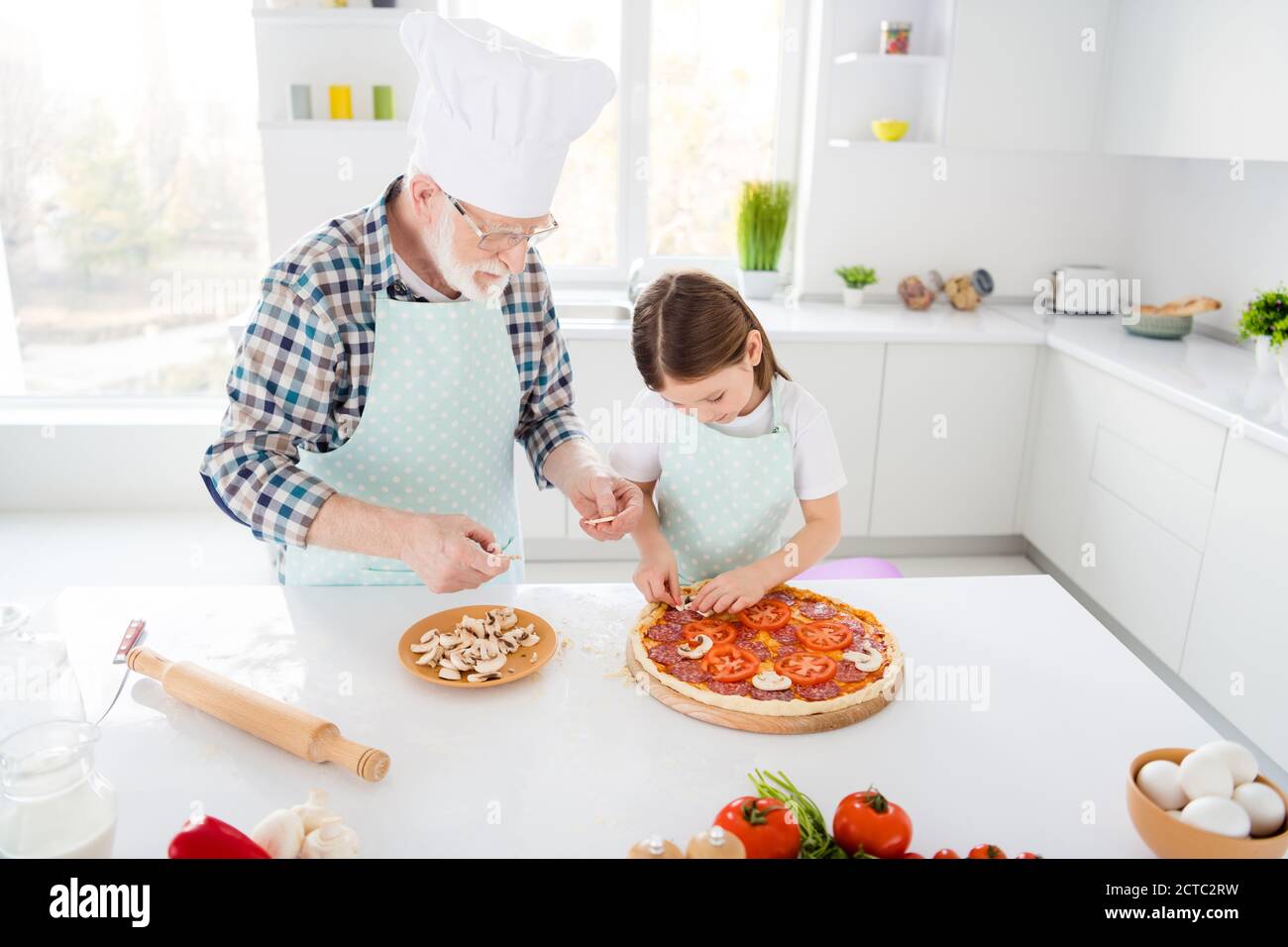 Portrait of his he her she focused grey-haired grandparent grandchild teaching cook homemade vegs vegetarian pizza mushroom workshop support in light Stock Photo