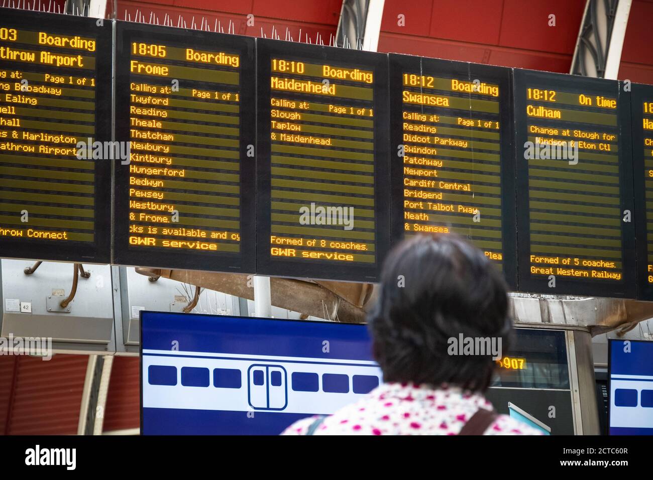Back view of a passenger looking at train timetable at London Paddington railway station Stock Photo