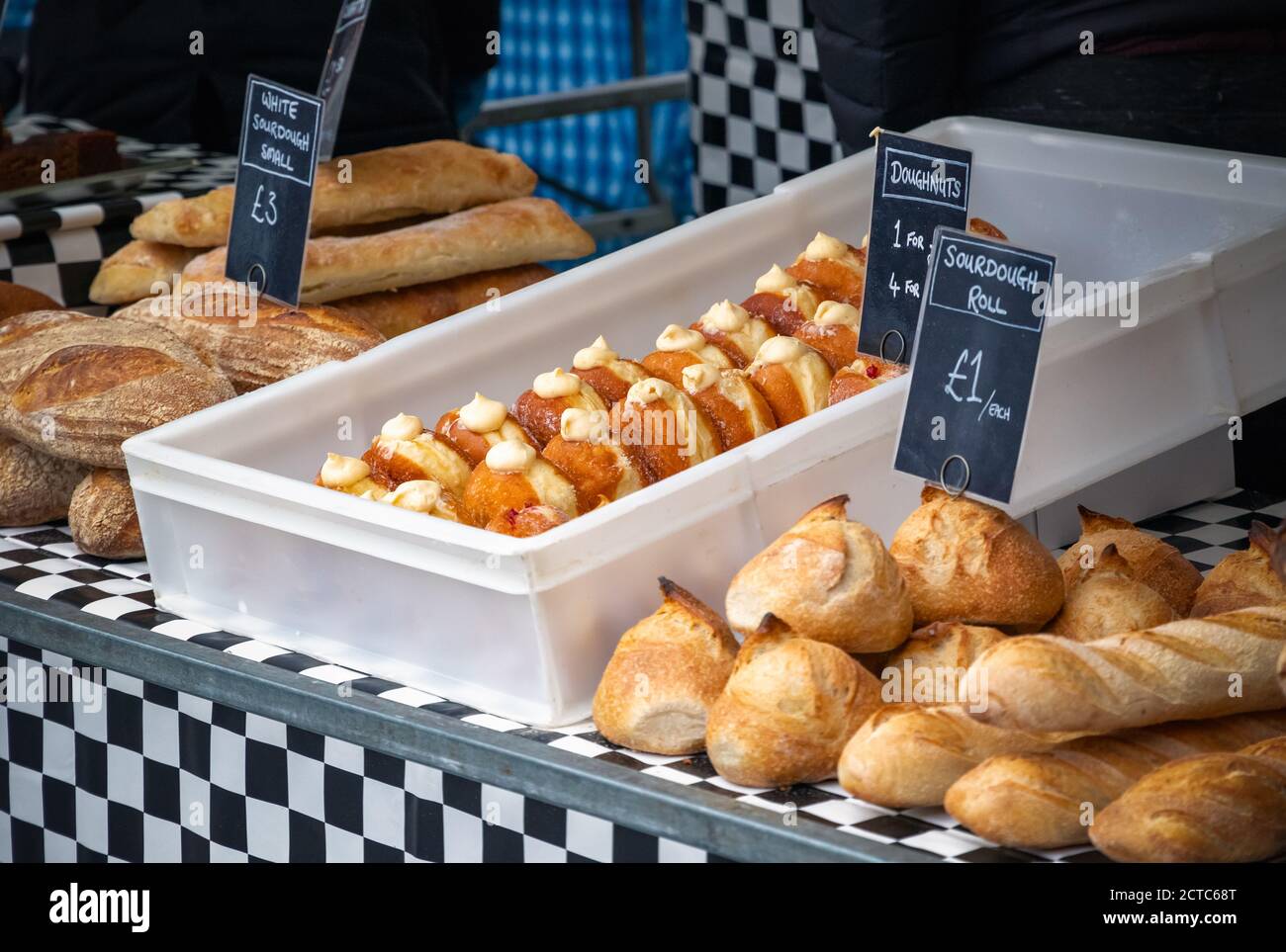 Fresh doughnuts and sourdough breads on display at King's Cross outdoor food market Stock Photo