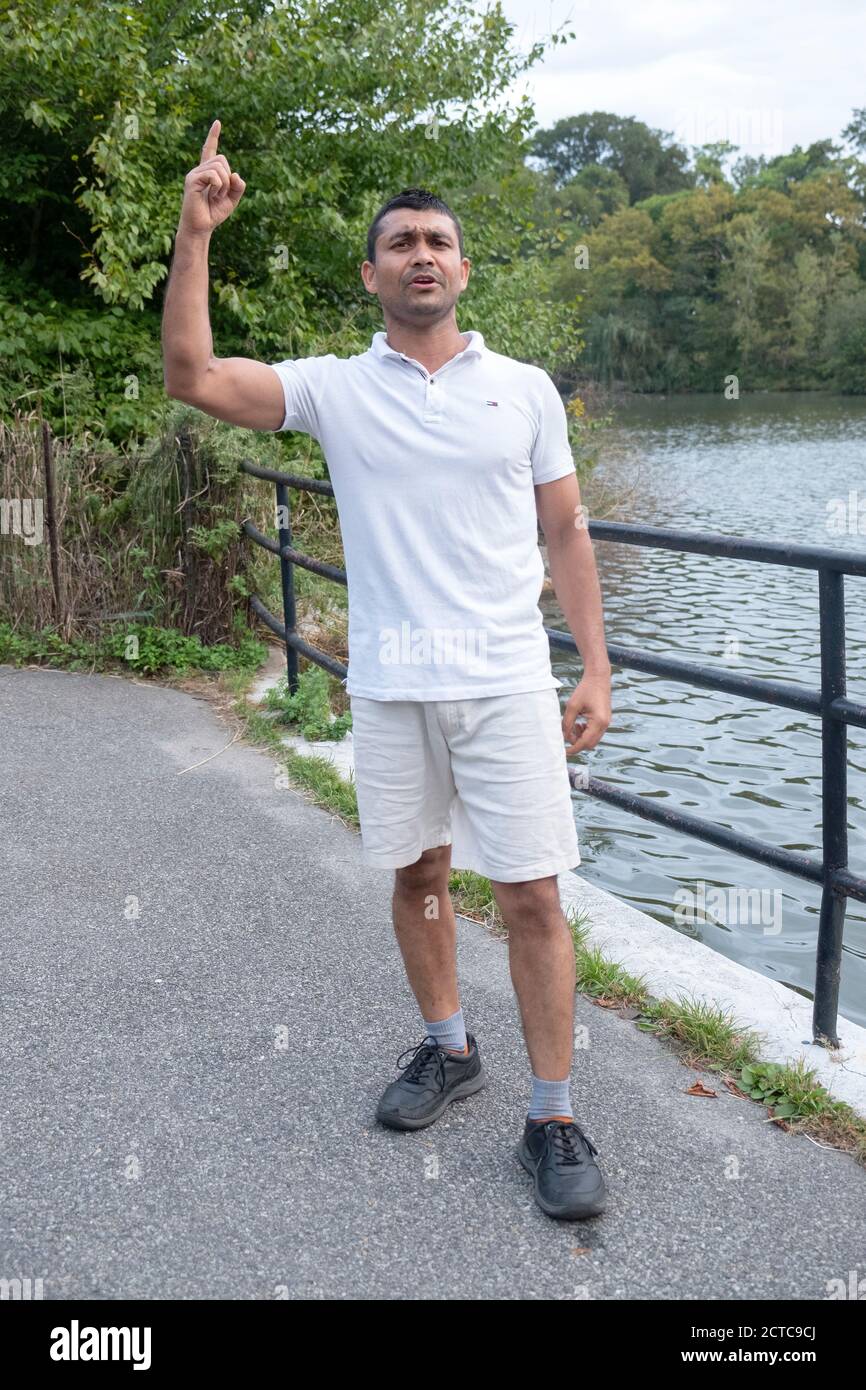 An immigrant man from Bangladesh recites religous Moslem poetry in Bengali. At a park in Flushing, Queens, New York City. Stock Photo