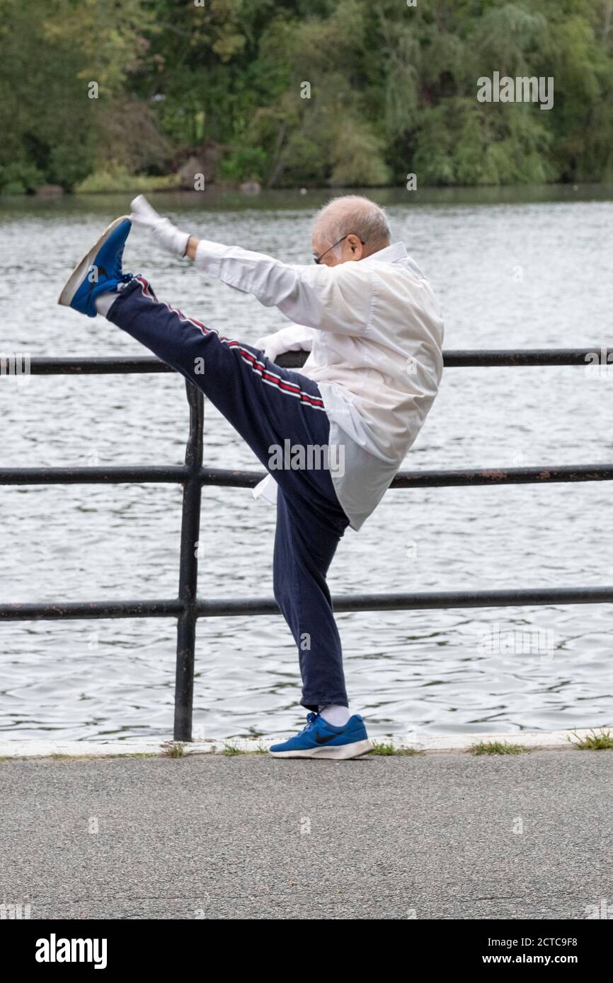 A nimble flexible senior citizen does some extreme stretching while warming up for an exercise walk. In a park in Queens, New York City. Stock Photo