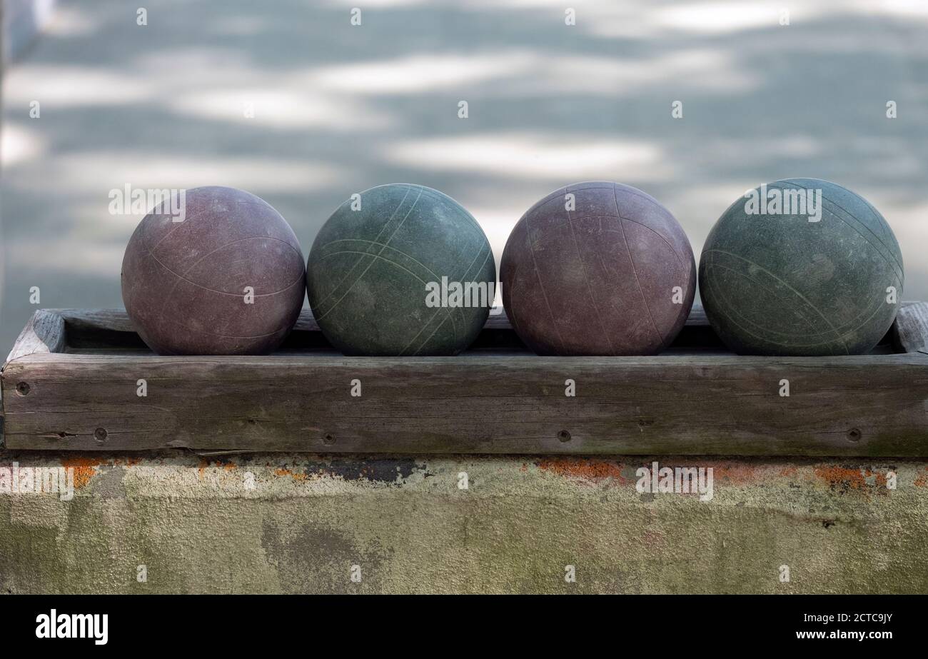 A still life of four well worn bocce balls in a rack at a park in Flushing, Queens, New York City. Stock Photo