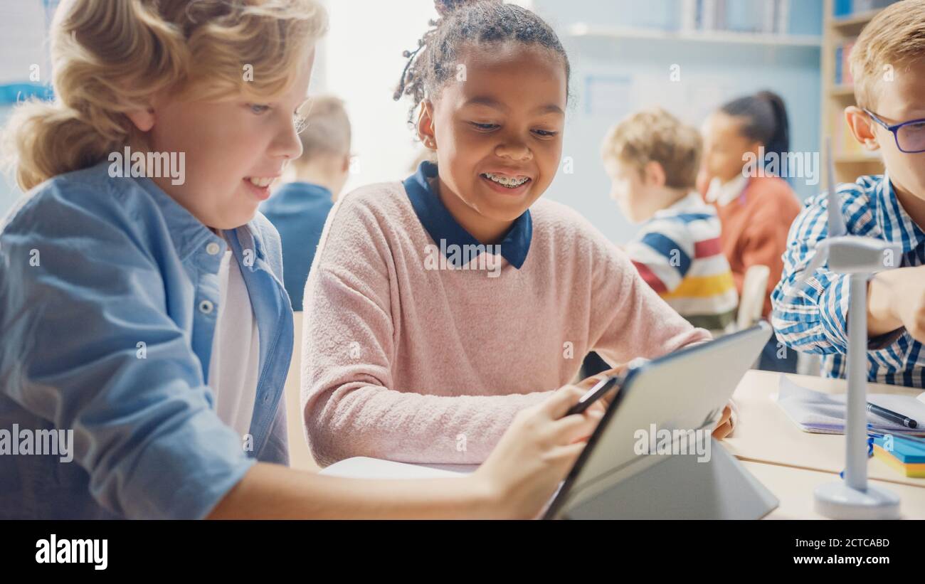 In the Elementary School: Girl and a Boy Work as a Team Using Tablet ...