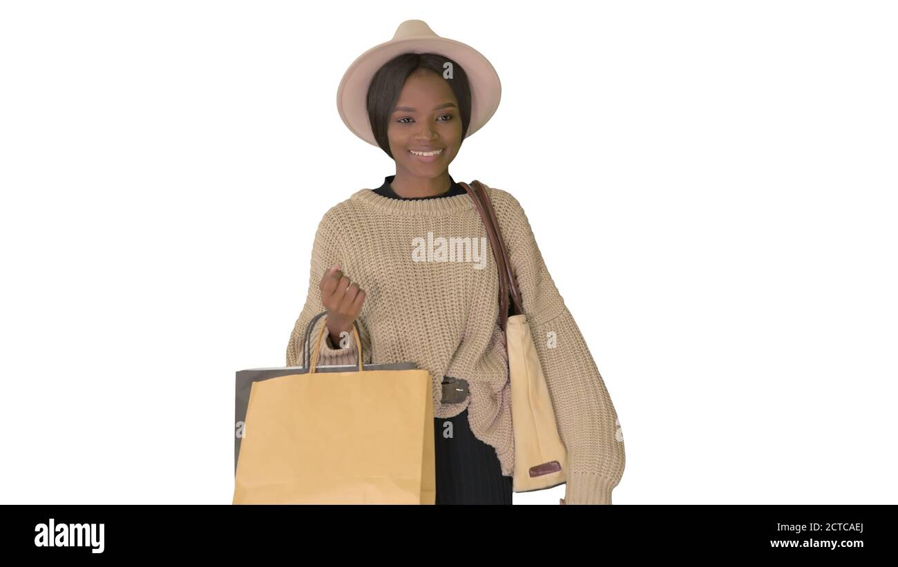 Happy african american woman in hat and knitwear walking with sh Stock Photo