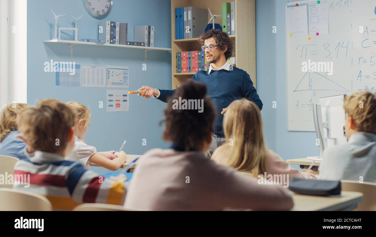 Enthusiastic Teacher Explains Lesson to a Classroom Full of Bright Diverse Children, Teaches Geometry, Math. In Elementary School Group of Bright Stock Photo